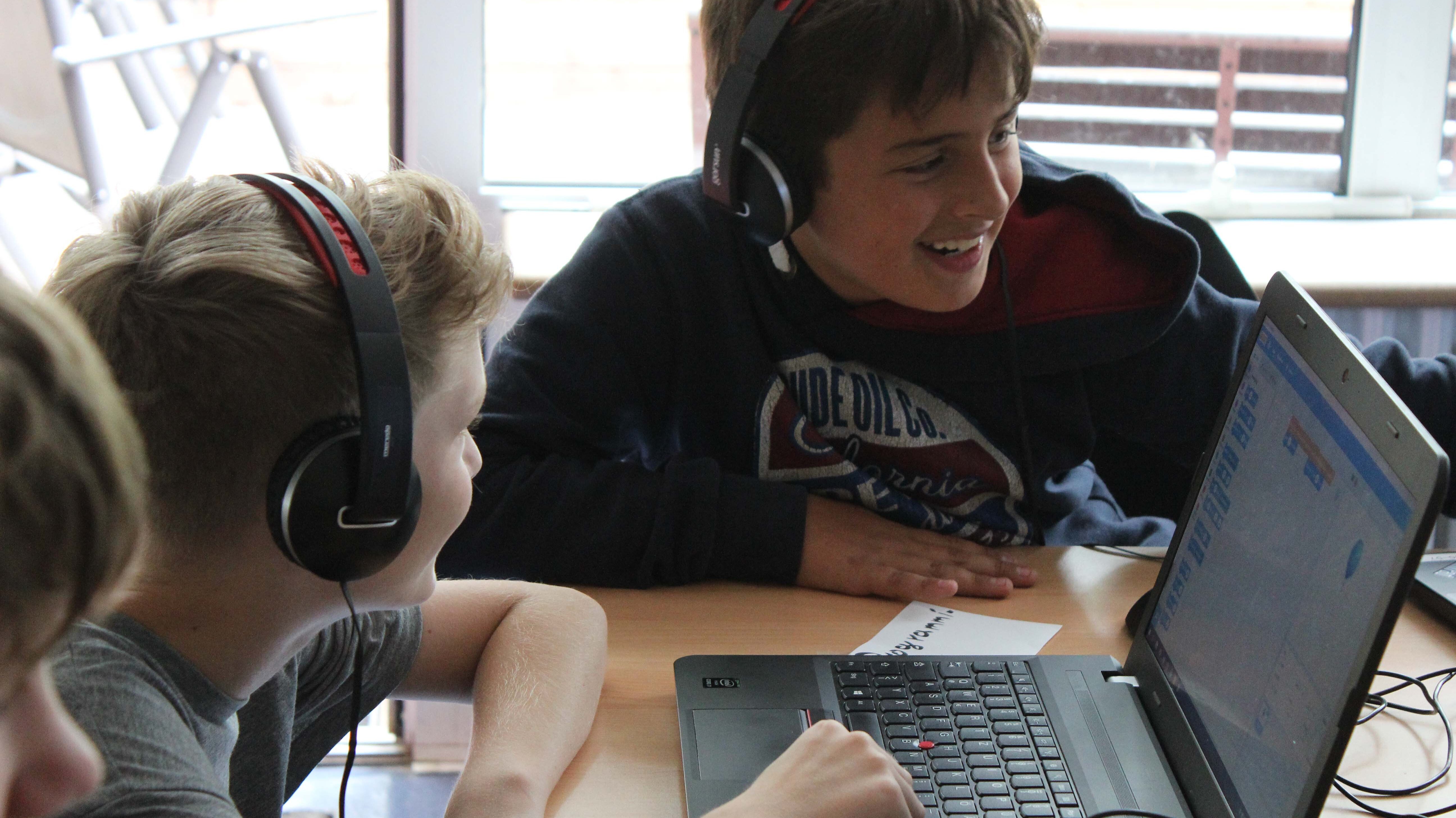 Jungen sitzen mit Kopfhörern vor einem Laptop